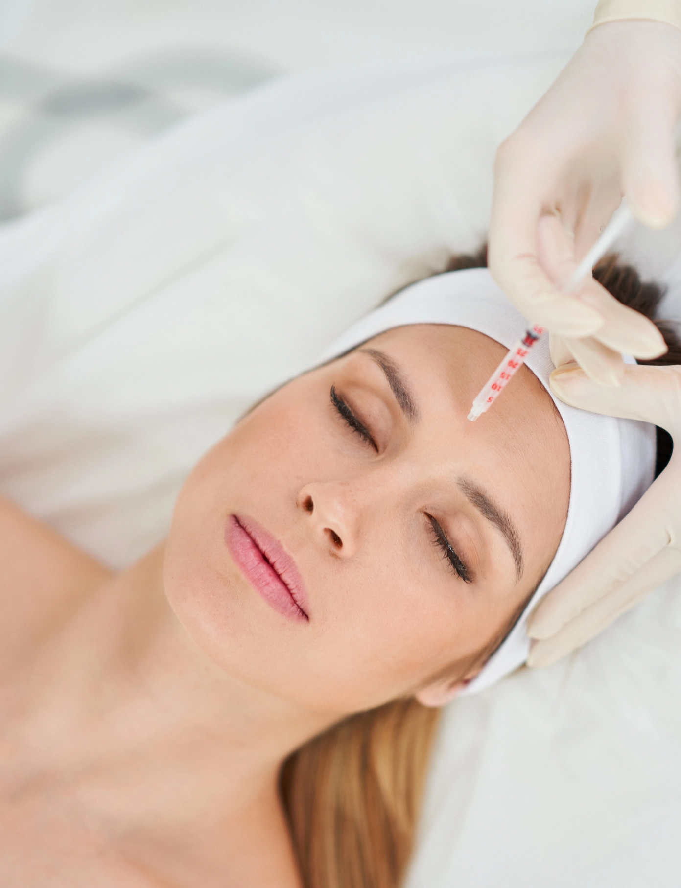 A young woman receives a Botox injection from a professional injector.